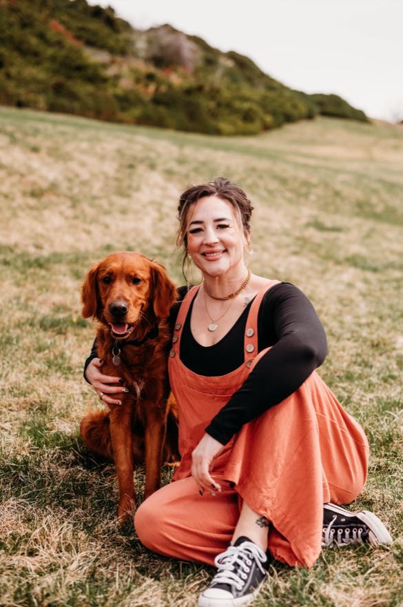 Shana Sklar sitting in a field with her golden retriever